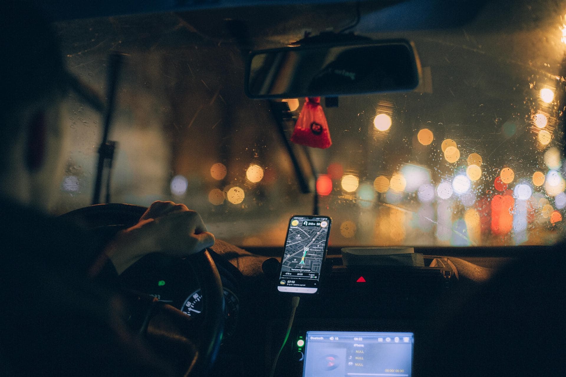 A driver's view at night, with a phone on the dashboard